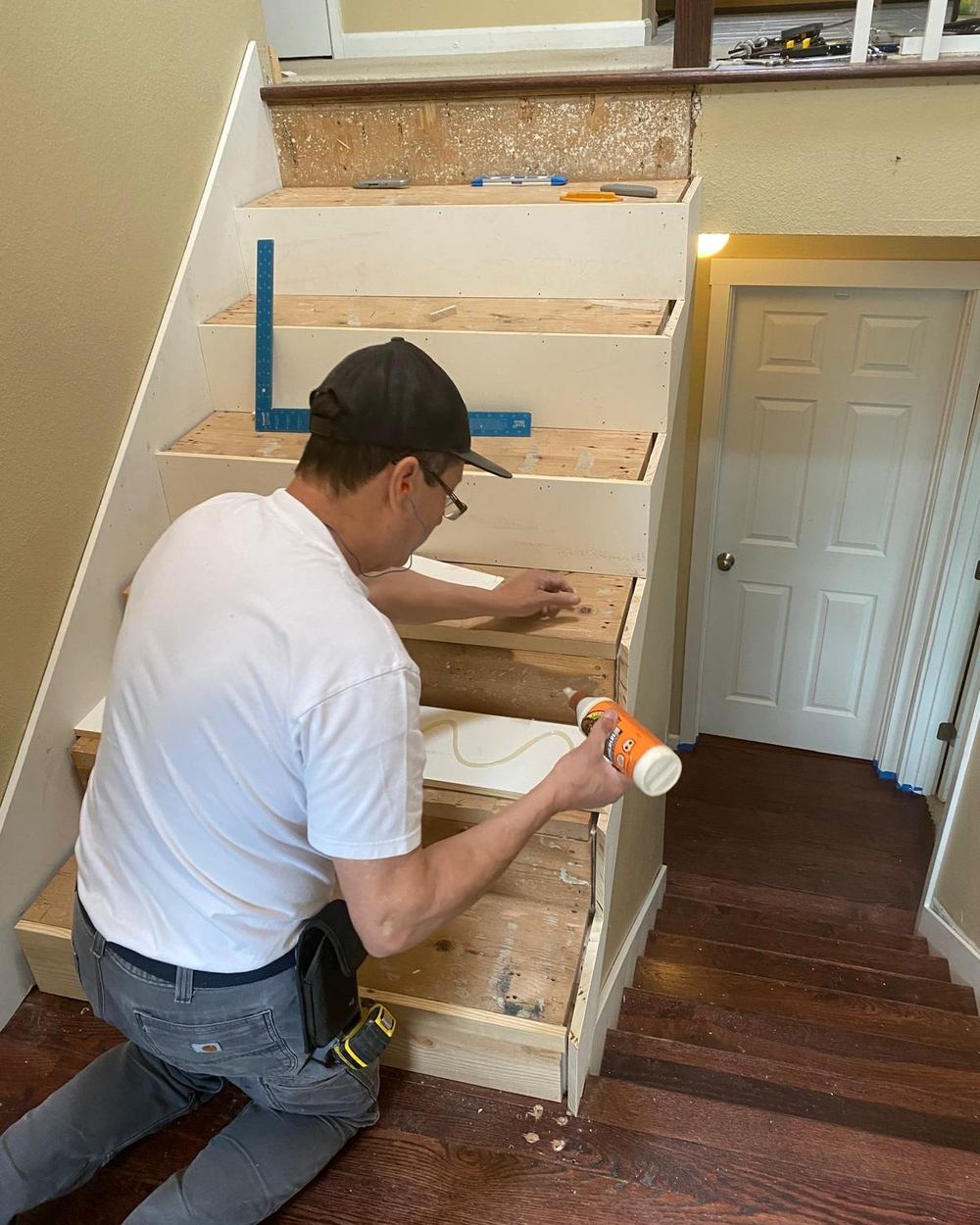 Contractor installing a new stair tread on a staircase with wood risers