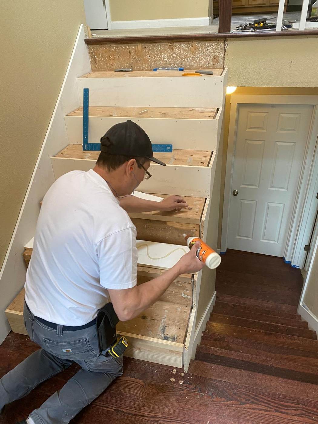 Contractor installing a new stair tread on a staircase with wood risers