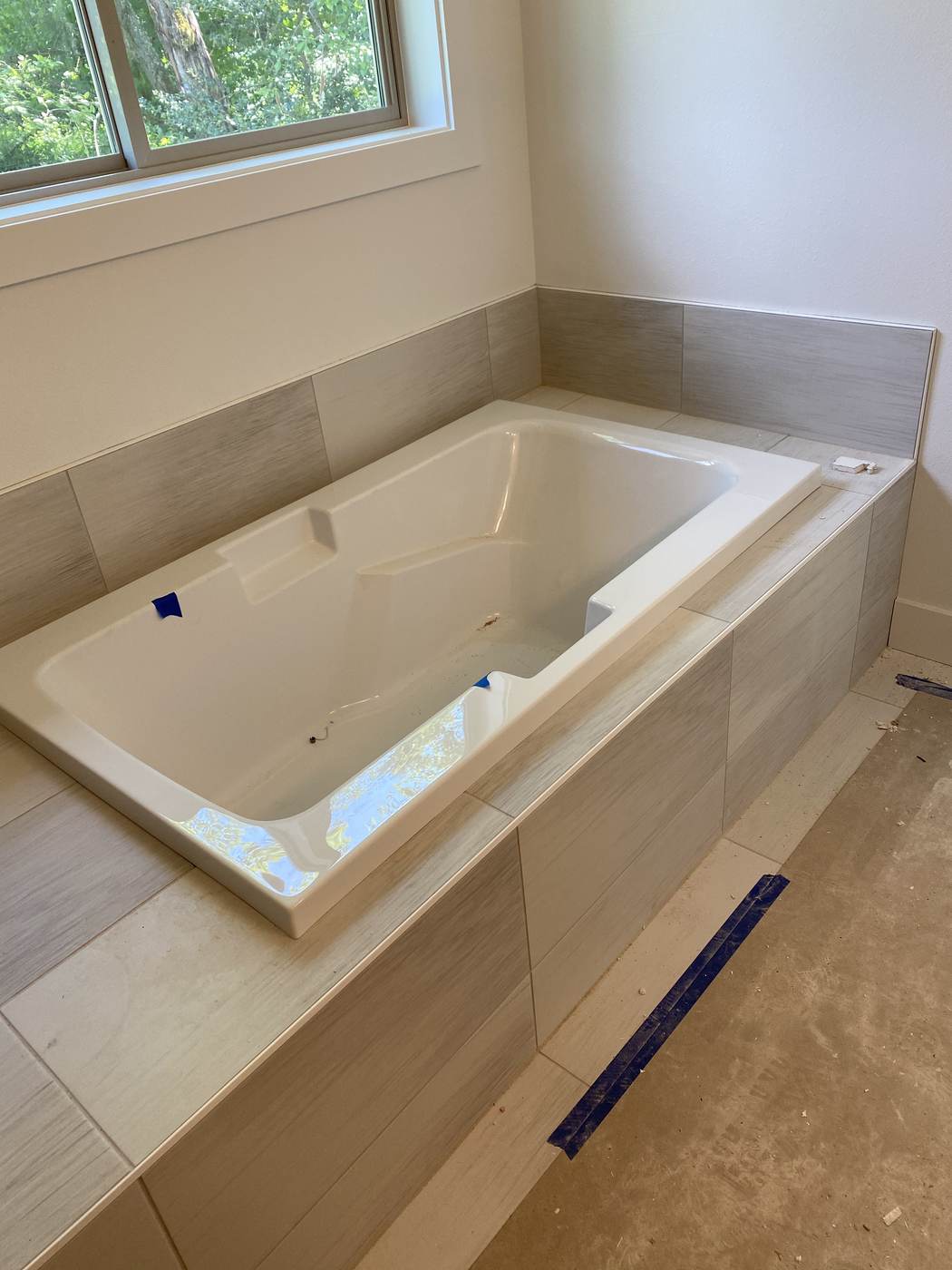 Drop-in tub set in a large format tile deck and wall.
