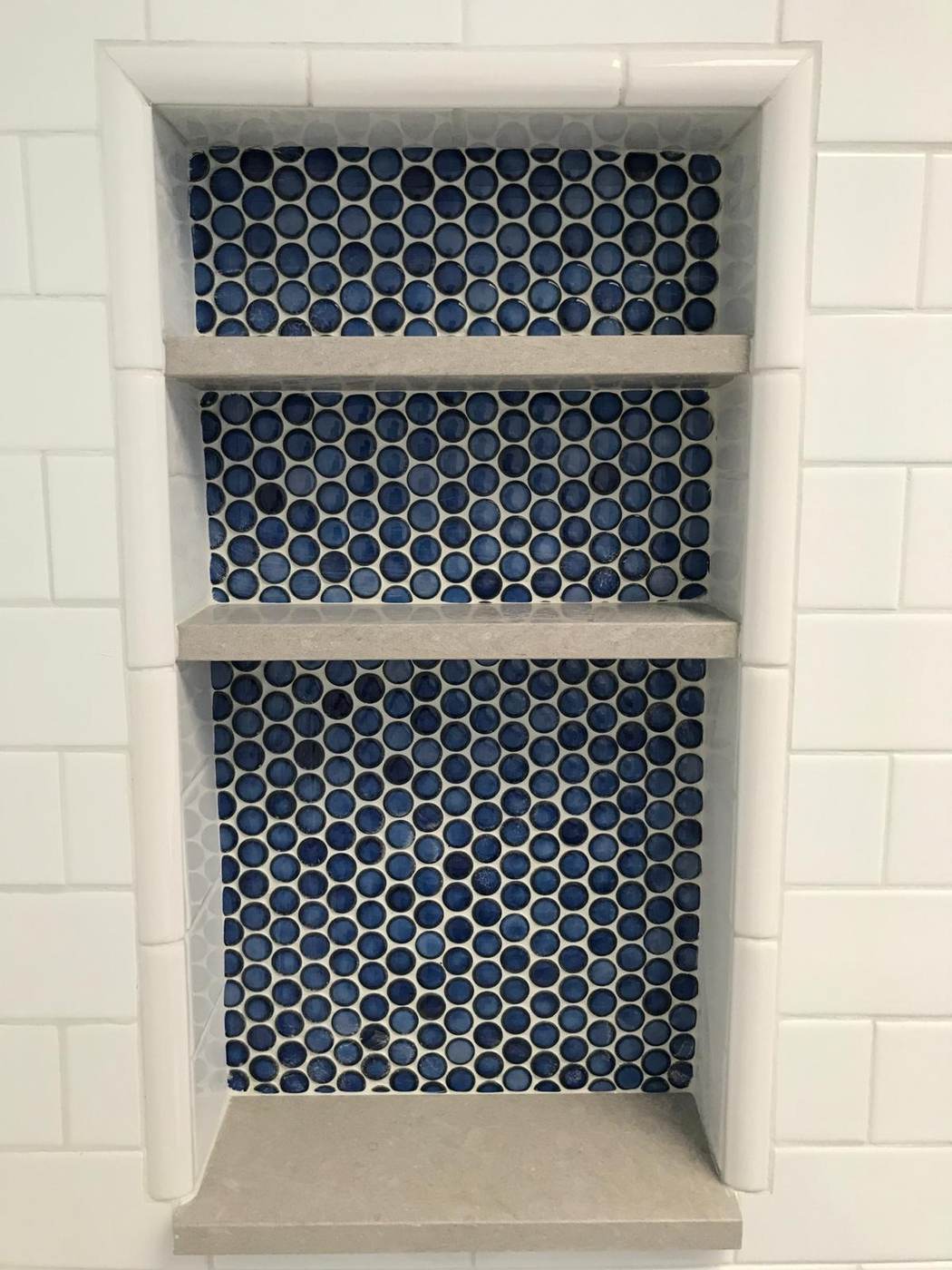 Recessed niche with blue penny tile and stone shelves.