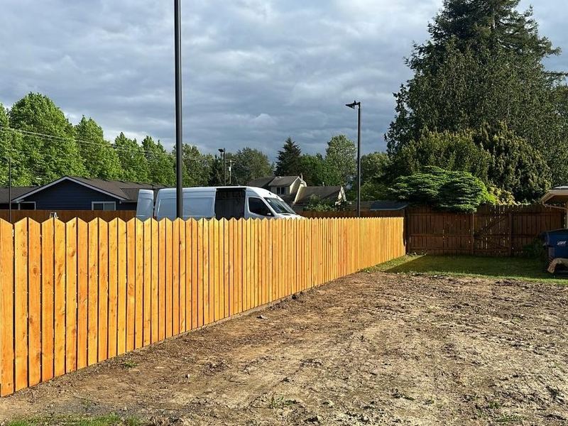 Long run of new wood privacy fence along the edge of a parking lot